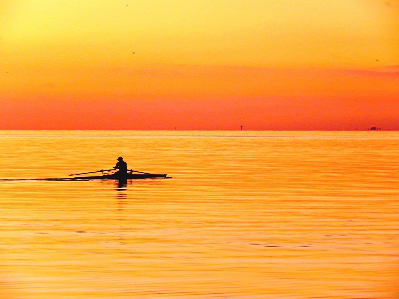 Silhouette man peddling boat in orange river