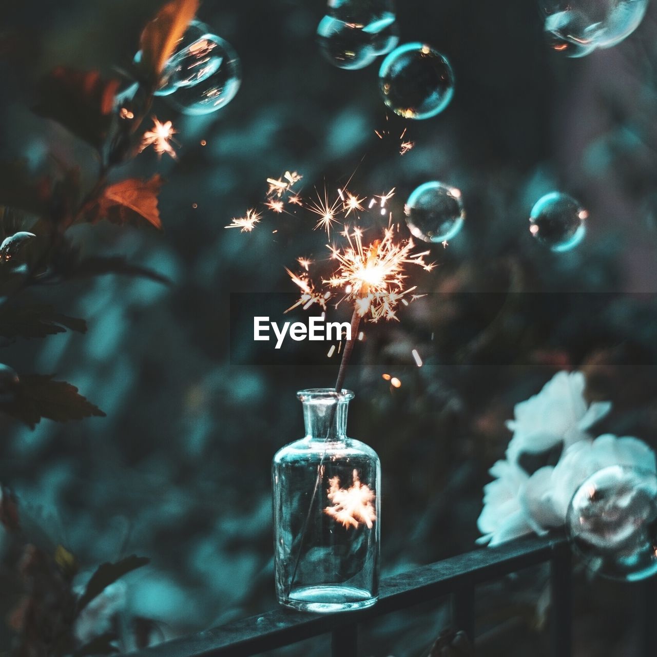 Lit sparkler in jar amidst bubbles