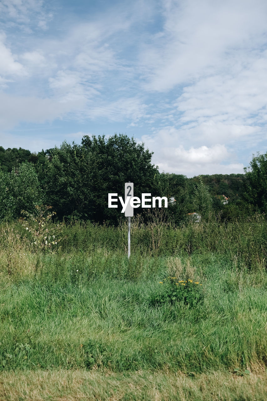 ARROW SIGN ON FIELD AGAINST SKY