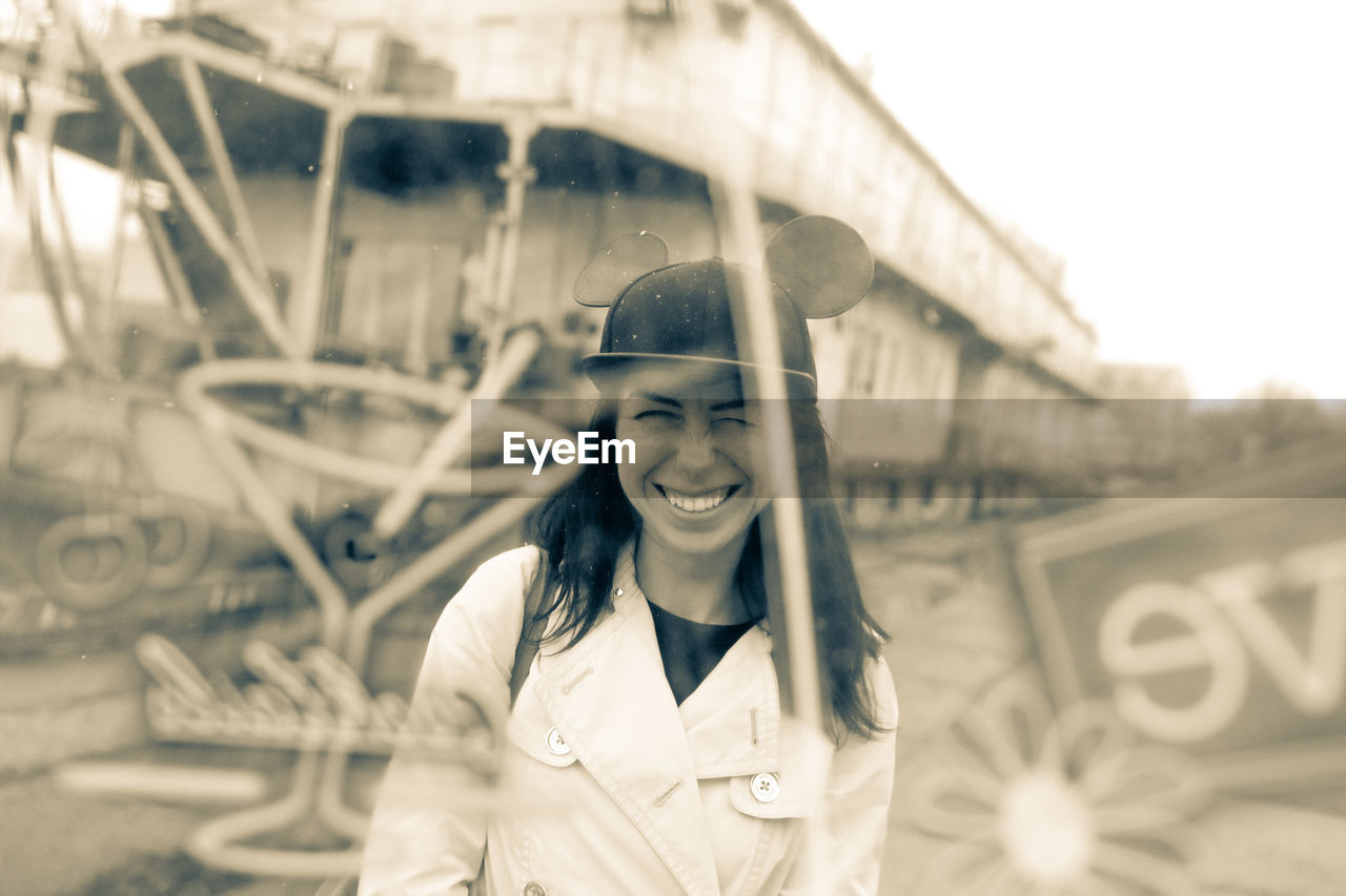 Smiling young woman standing with bridge in background