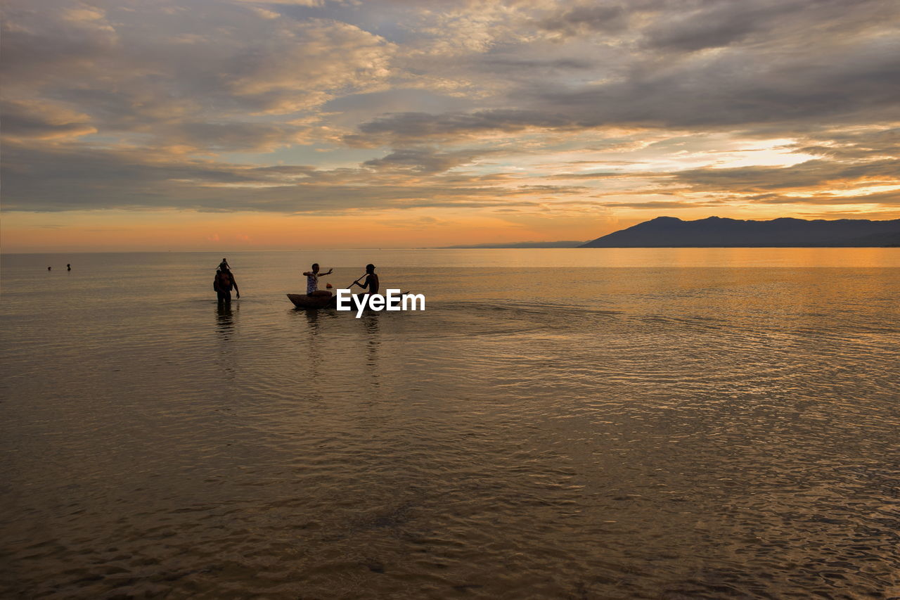 Young adults having fun at the beach against a golden sunset, kande beach, lake malawi, malawi