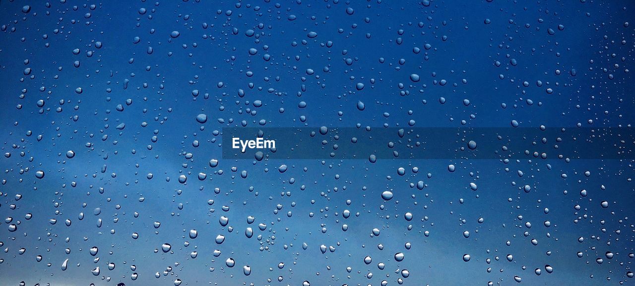 FULL FRAME SHOT OF WATER DROPS AGAINST BLUE SKY