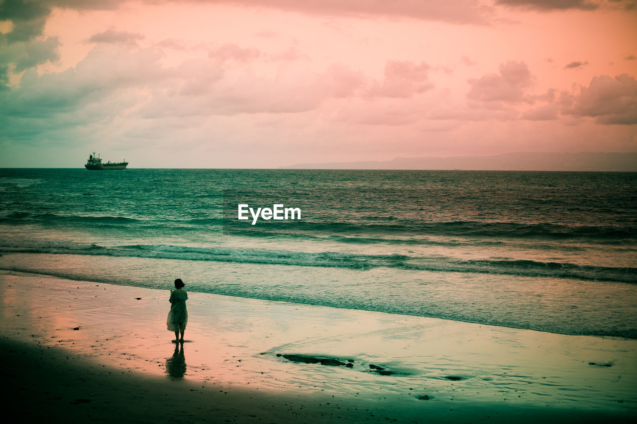 SILHOUETTE PERSON STANDING ON BEACH AGAINST SKY