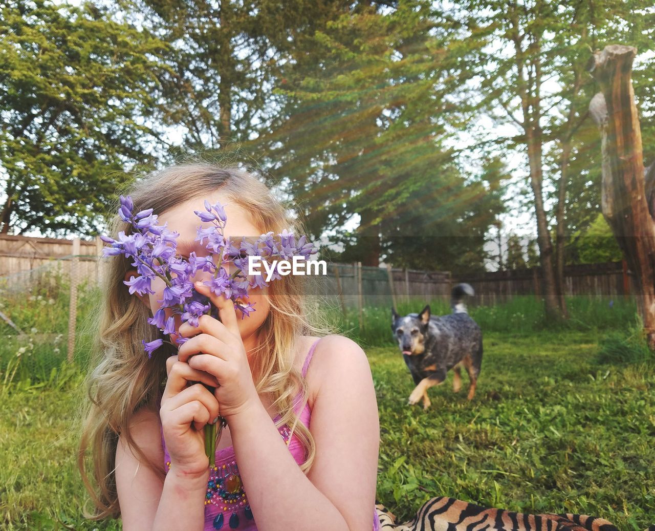 Girl hiding face with purple flowers in park