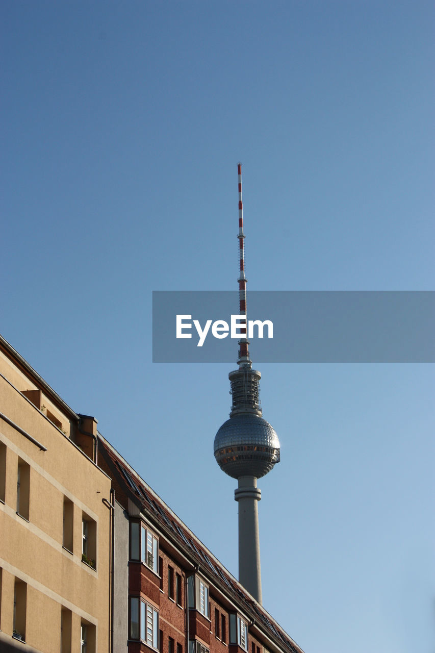 Low angle view of building and fernsehturm against clear blue sky