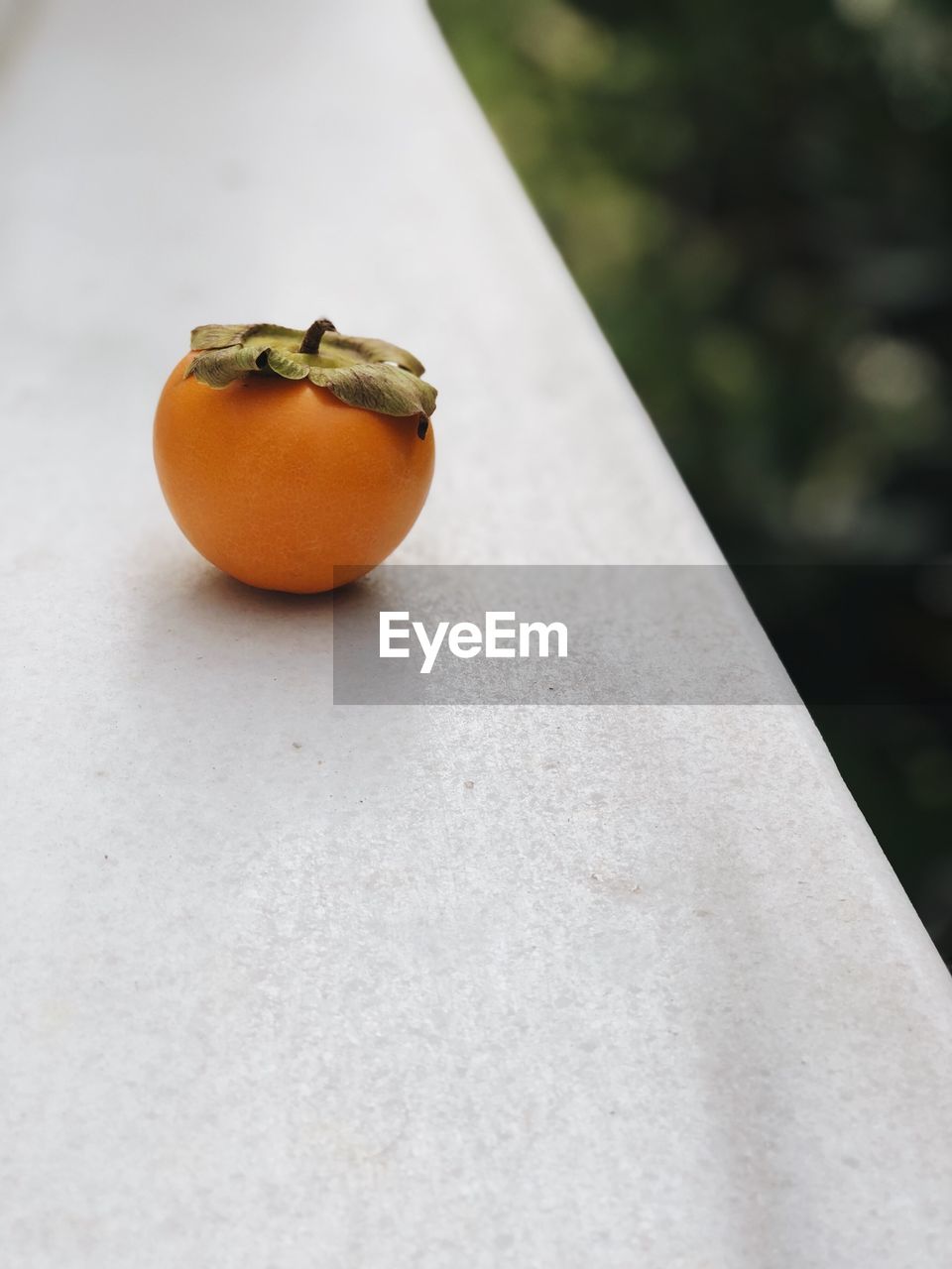 Close-up of persimmon on retaining wall outdoors