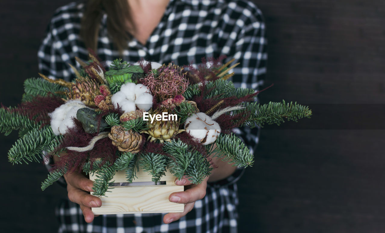 MIDSECTION OF WOMAN HOLDING BOUQUET OF FLOWERING PLANTS