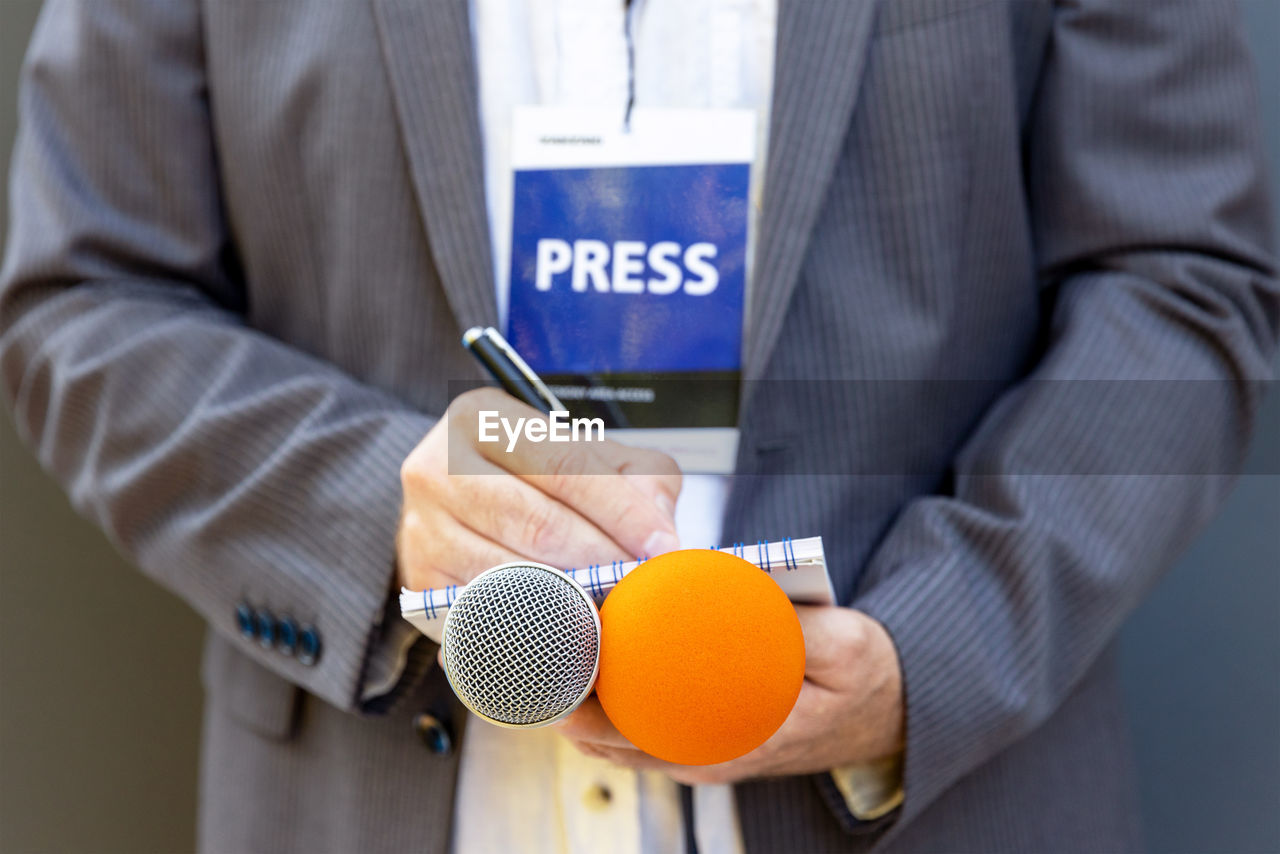 Correspondent or journalist at media event, holding microphone, writing notes. journalism concept.