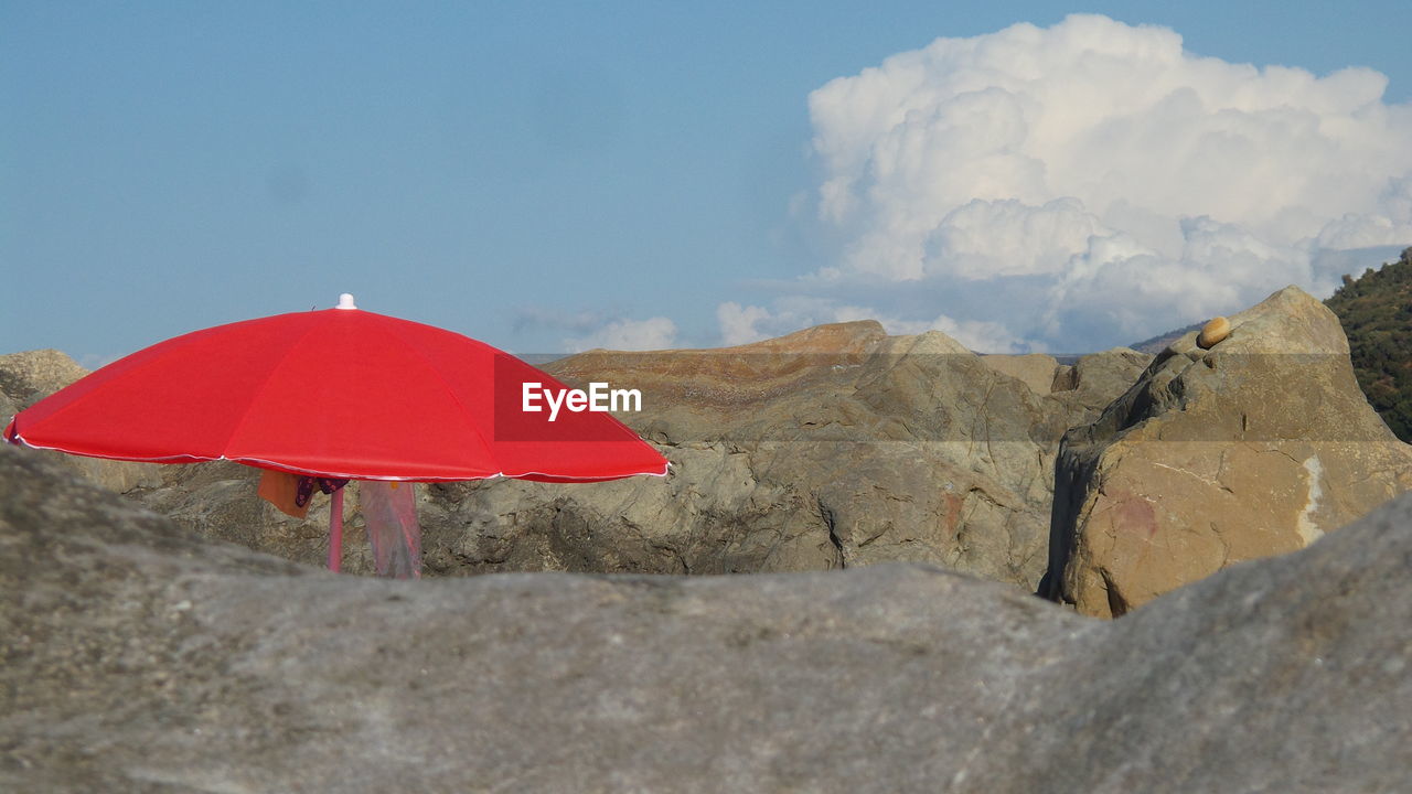 Red umbrella on mountain against sky