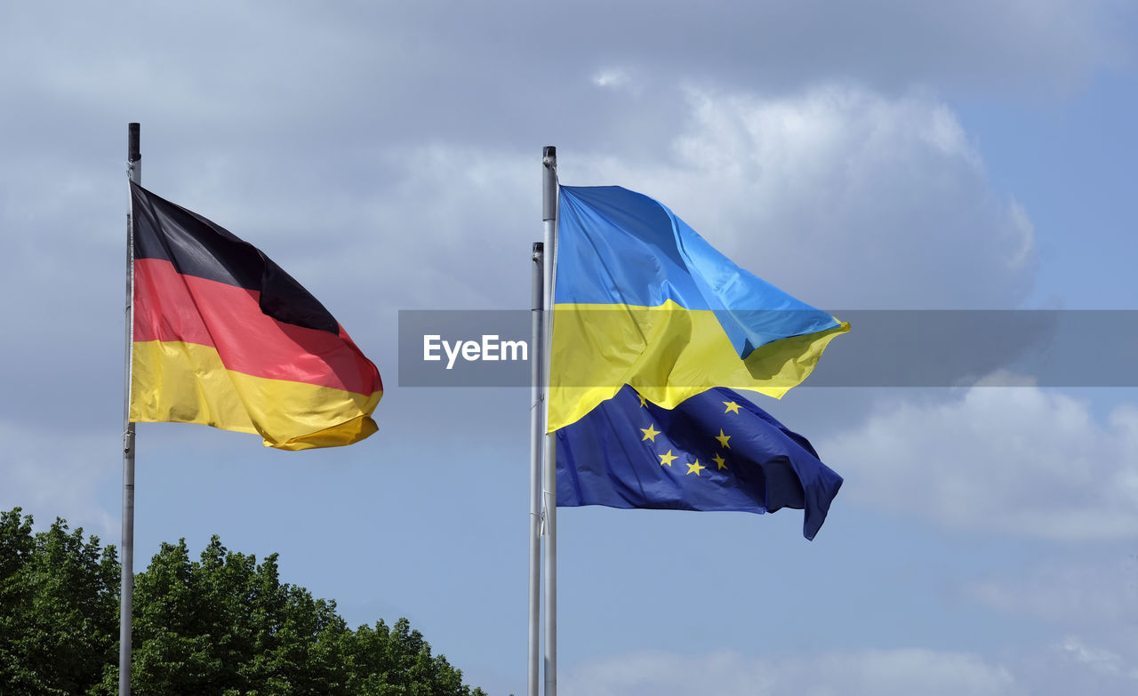 The flags of ukraine, germany, and the eu waving in the wind