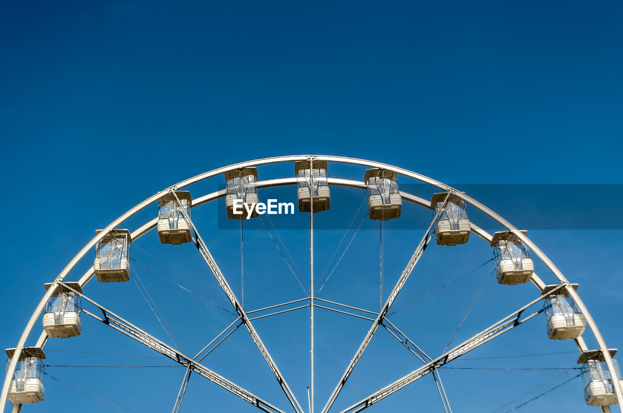 Low angle view of ferris wheel against clear blue sky