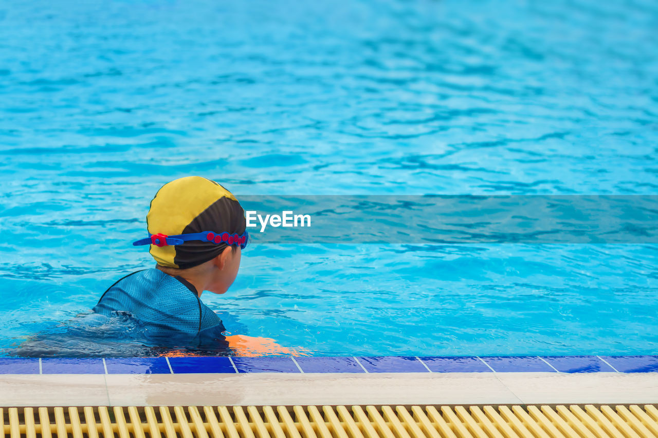 Boy swimming in blue pool