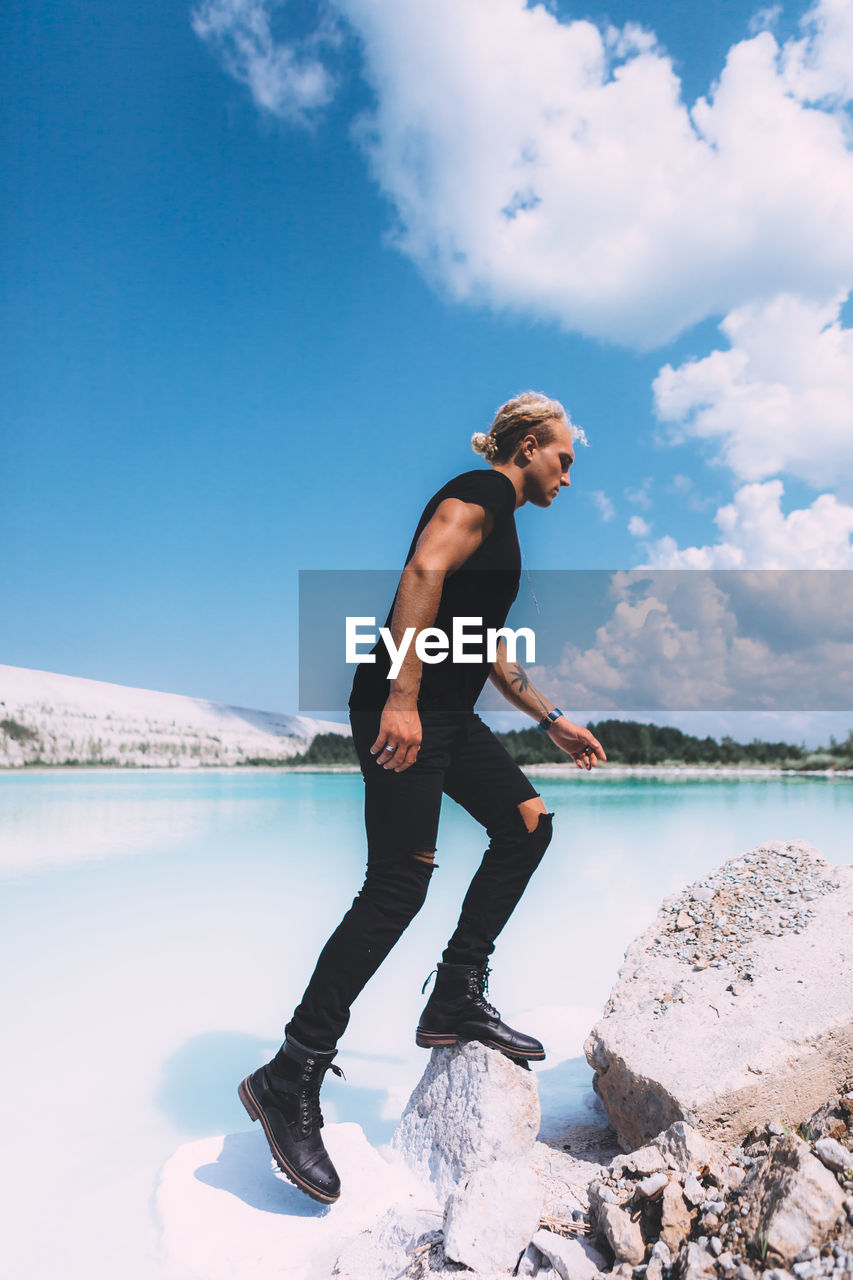 SIDE VIEW OF YOUNG MAN AGAINST LAKE AGAINST SKY