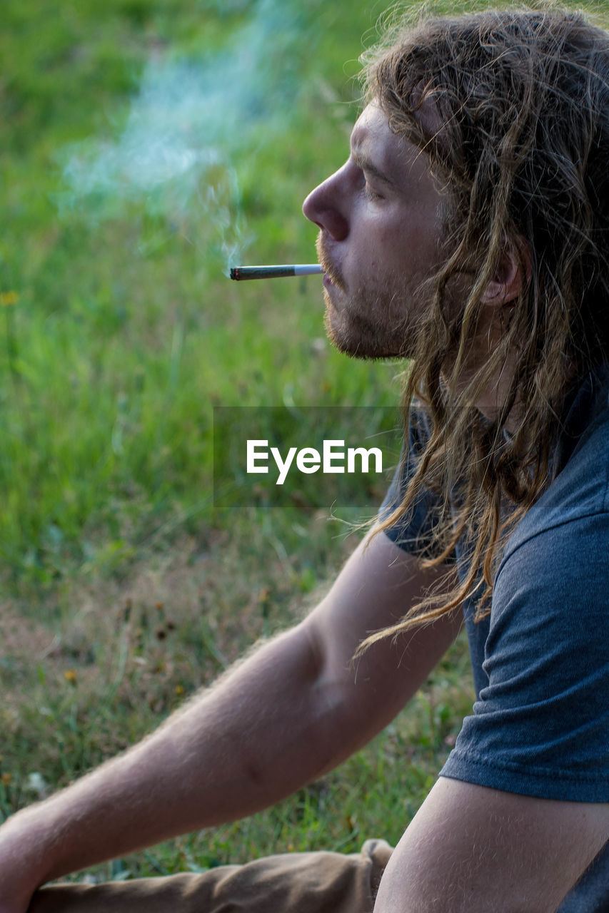 SIDE VIEW OF PERSON SMOKING CIGARETTE