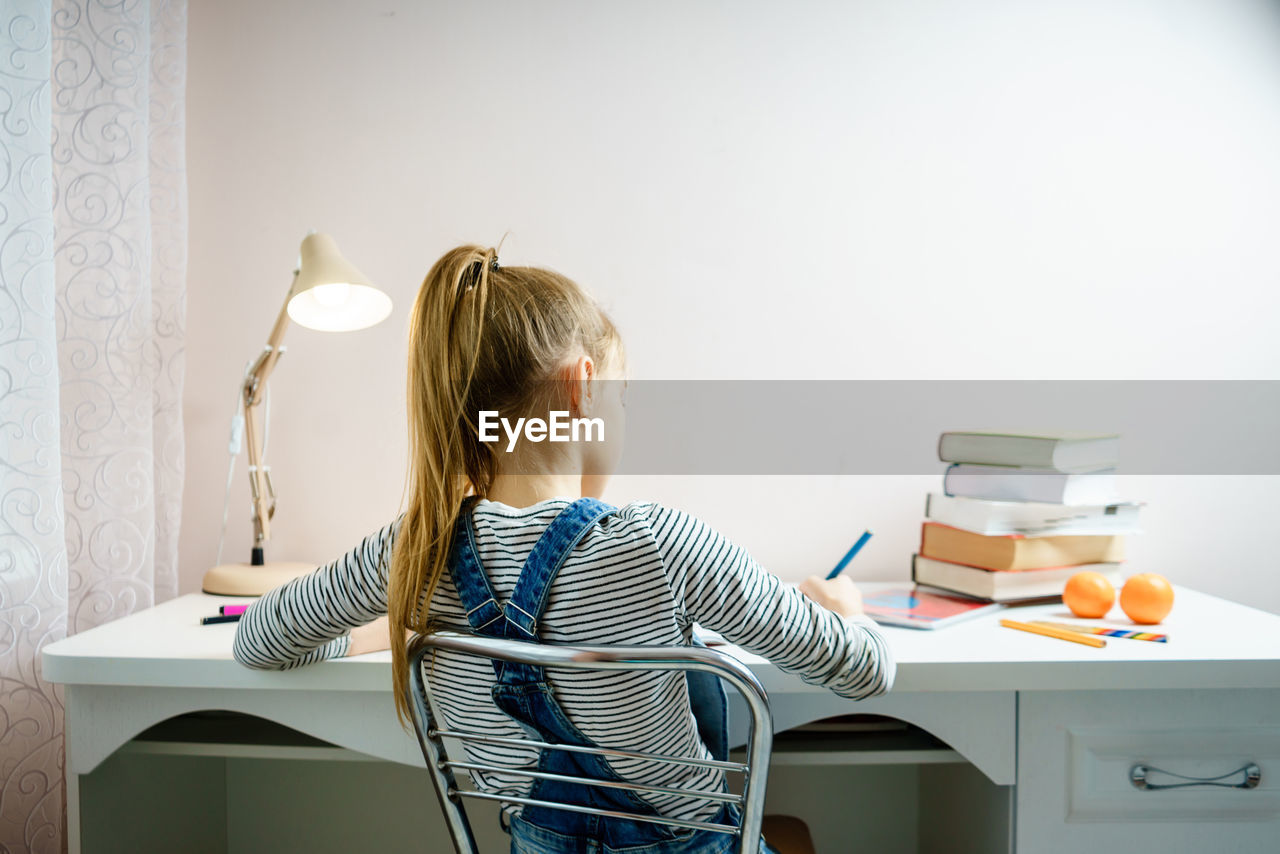 Rear view of girl studying at home