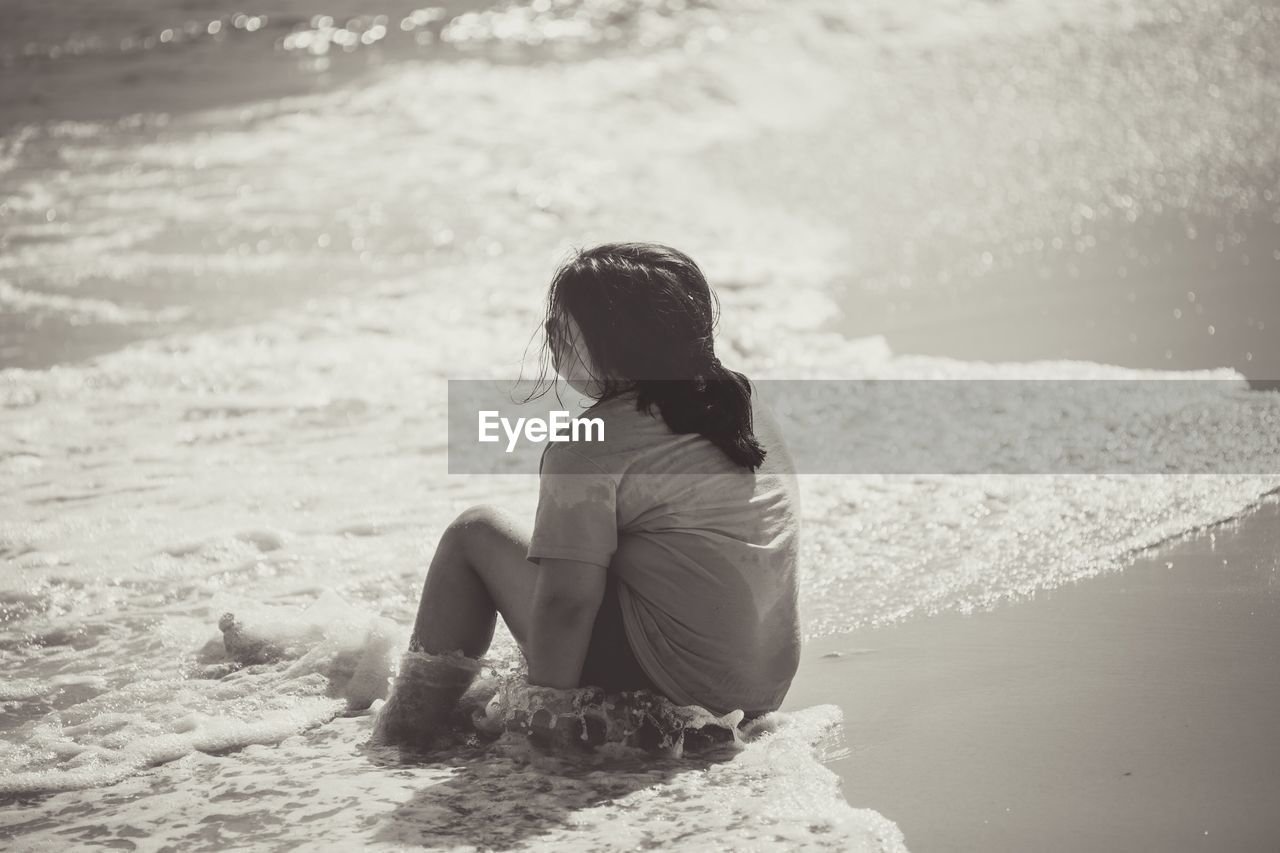 Rear view of girl sitting at beach