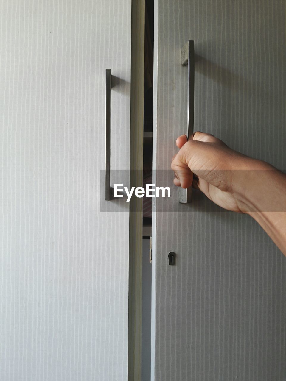 Cropped hand of person opening cabinet door