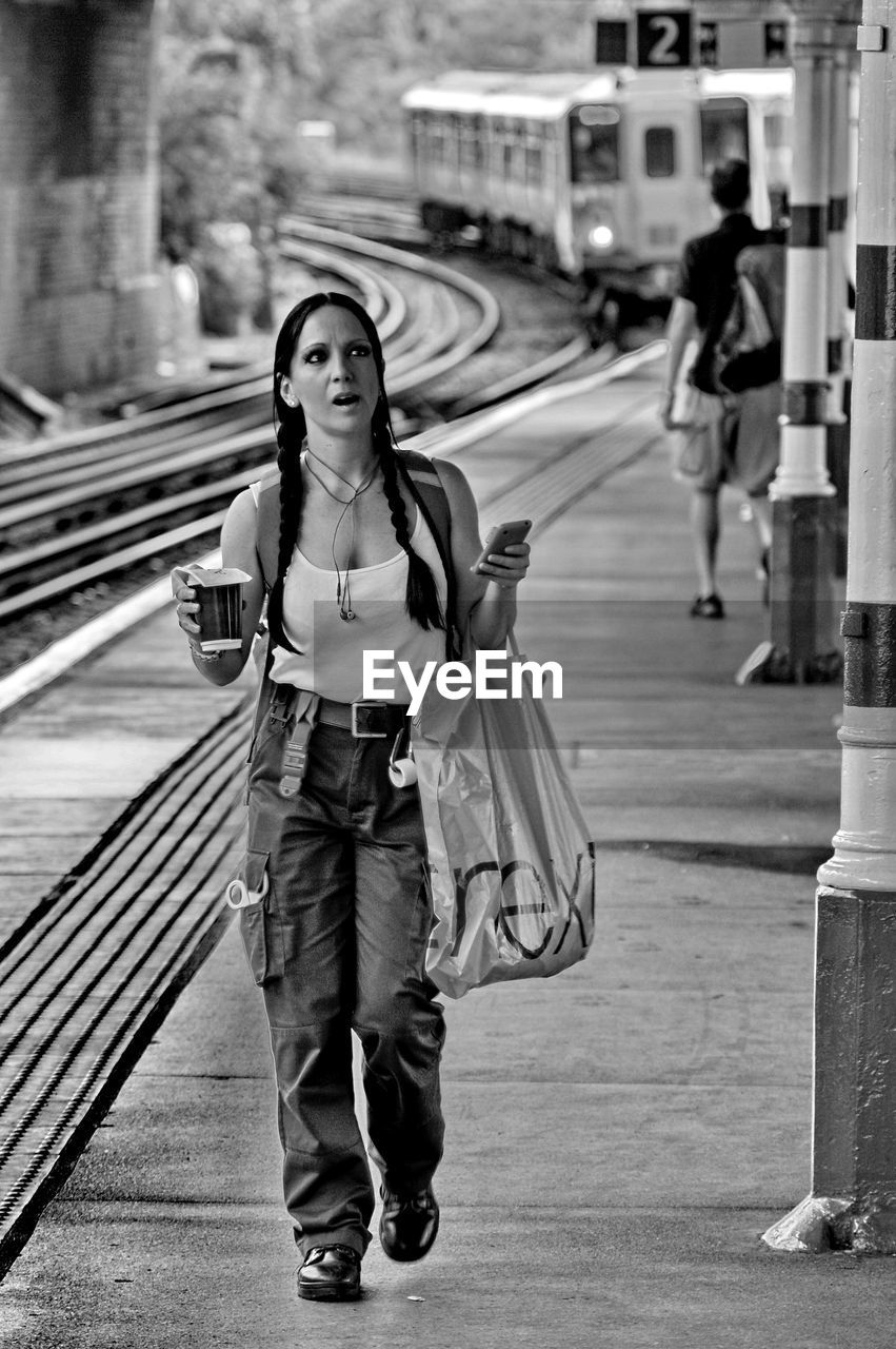 FULL LENGTH PORTRAIT OF WOMAN STANDING AGAINST CITY