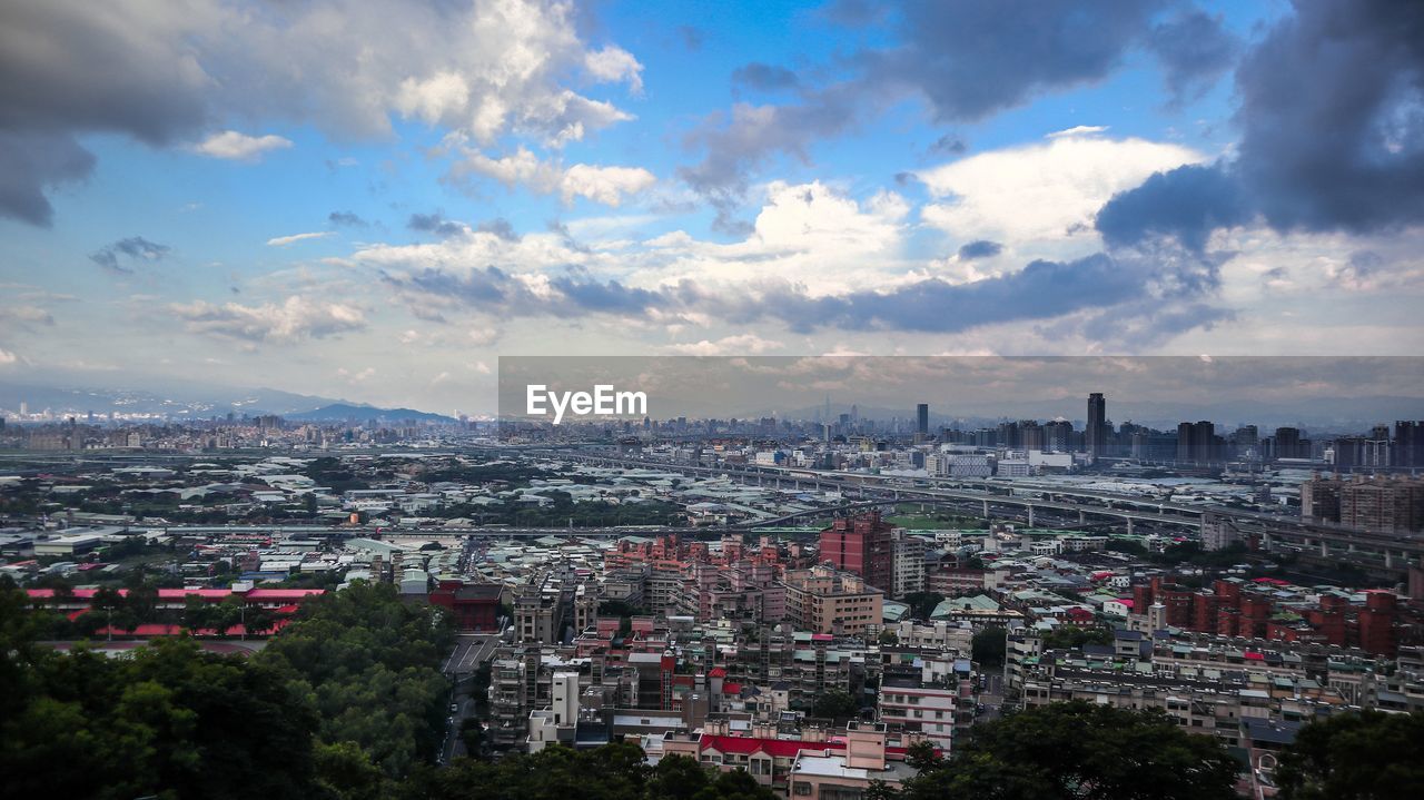 Aerial view of city buildings against cloudy sky