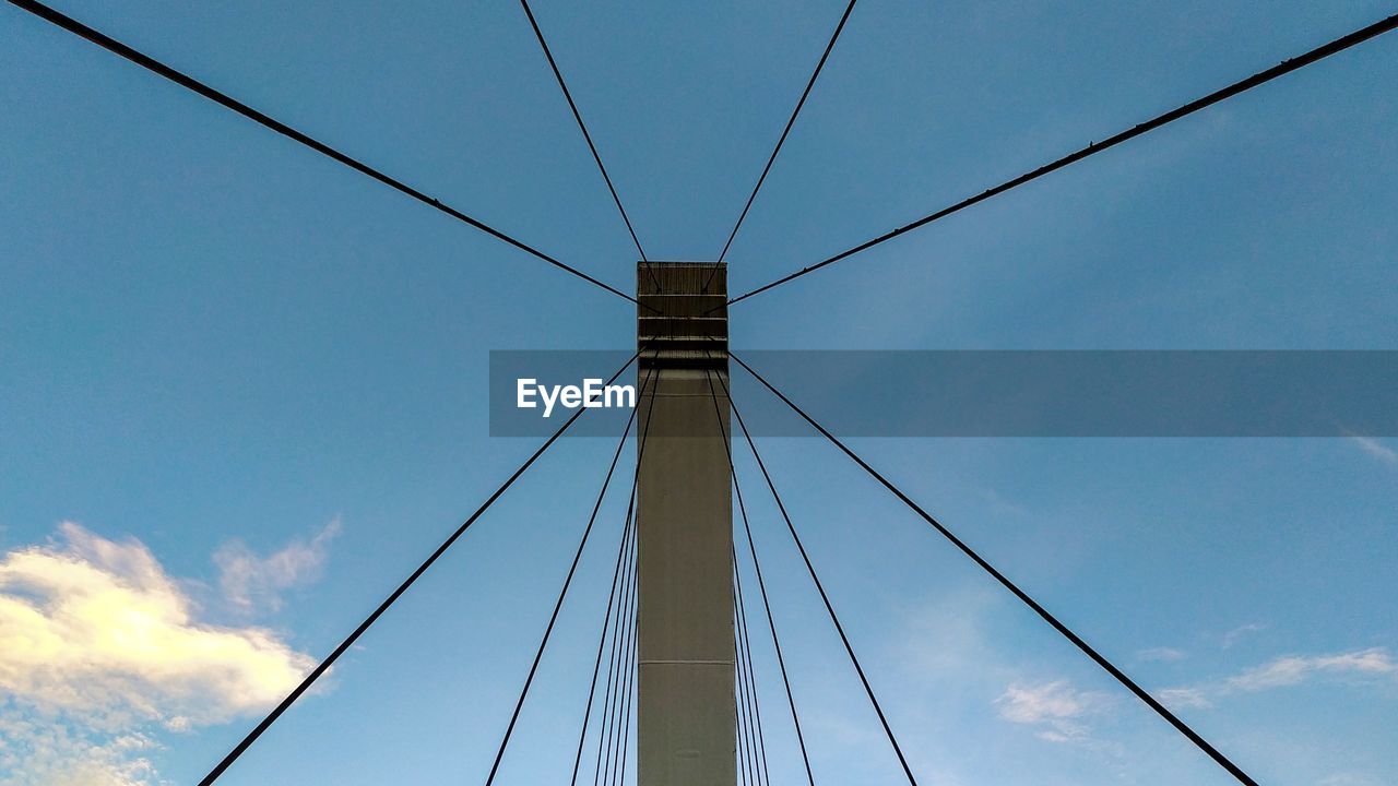 LOW ANGLE VIEW OF SUSPENSION BRIDGE CABLES AGAINST BLUE SKY