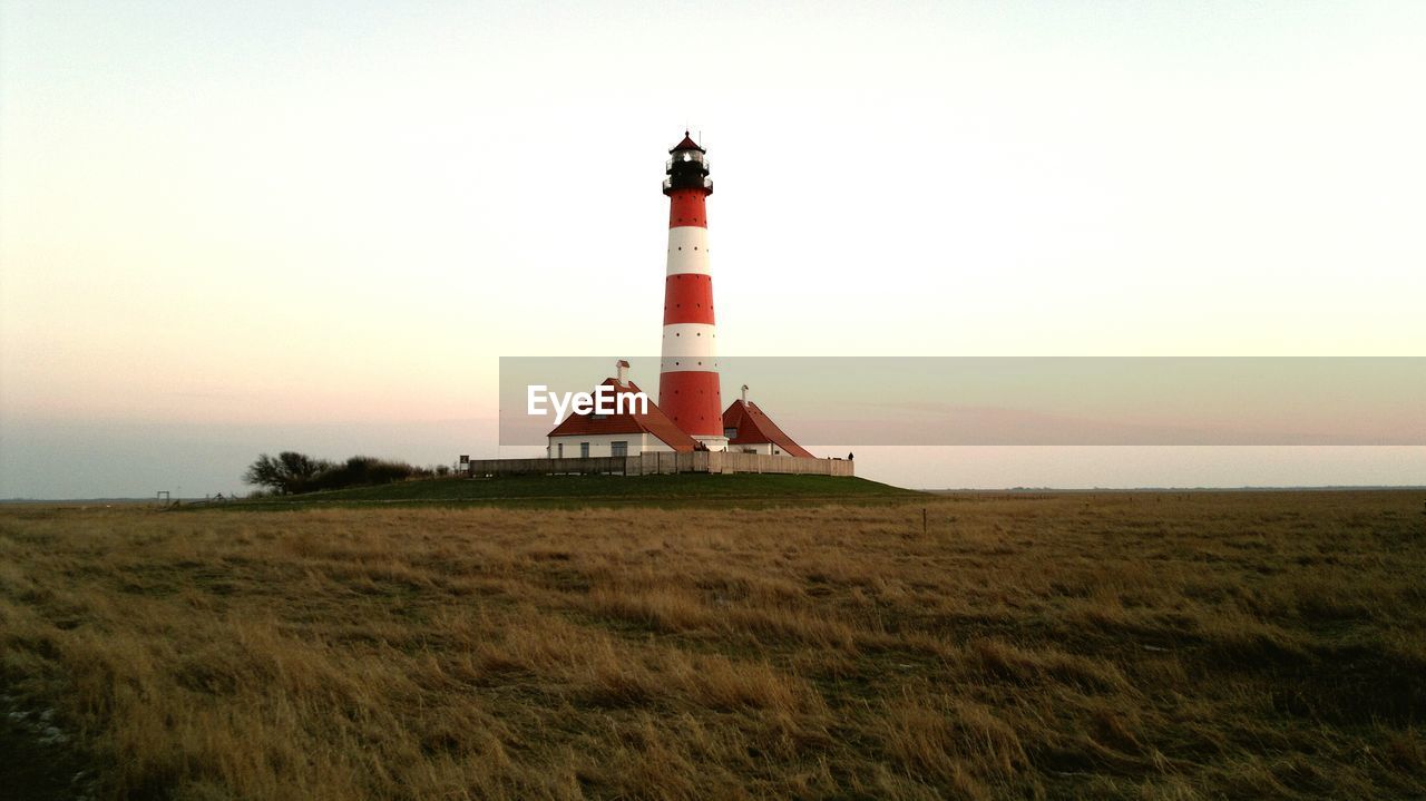 Lighthouse on field against sky