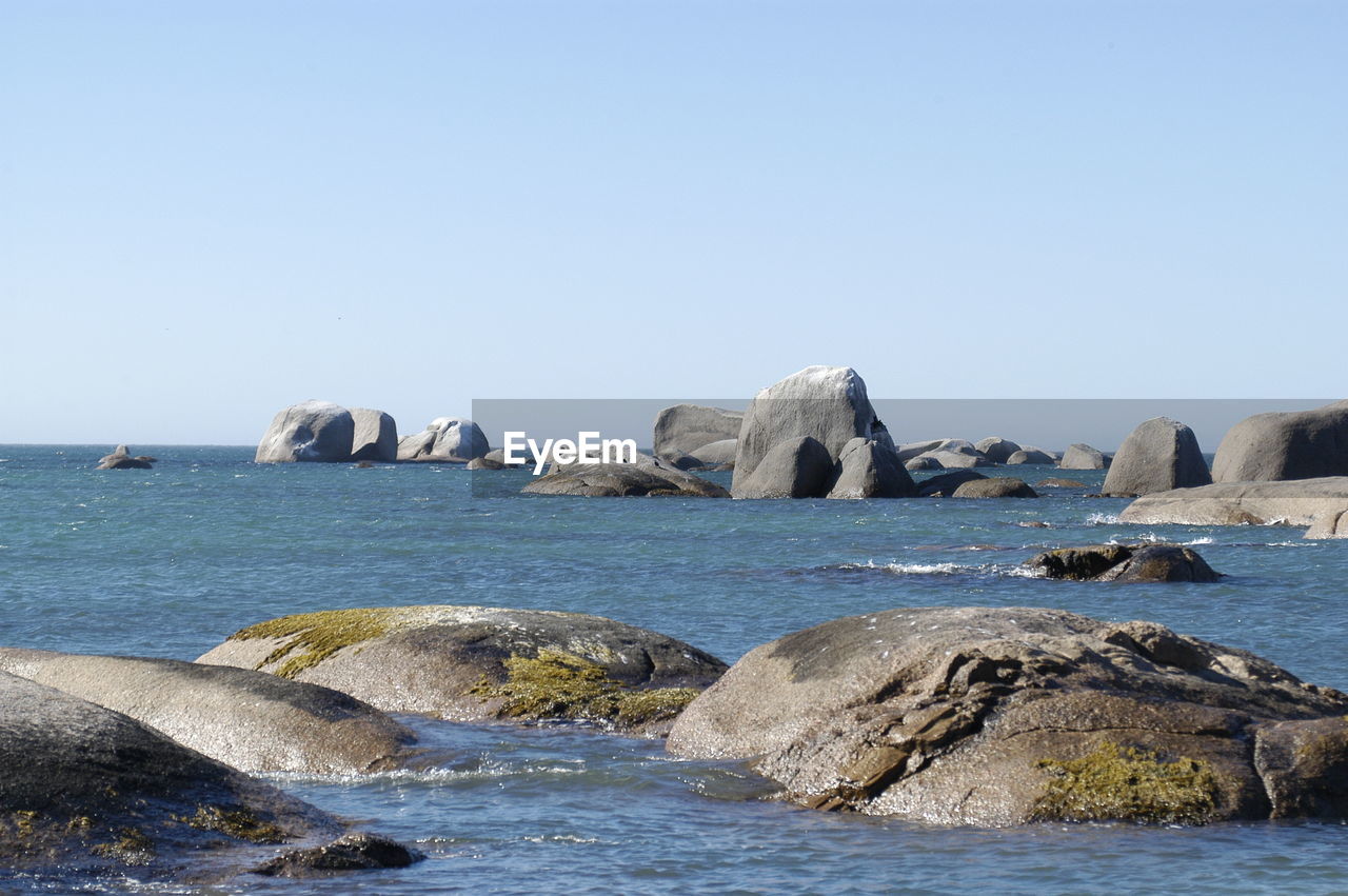 Rocks in sea against clear sky