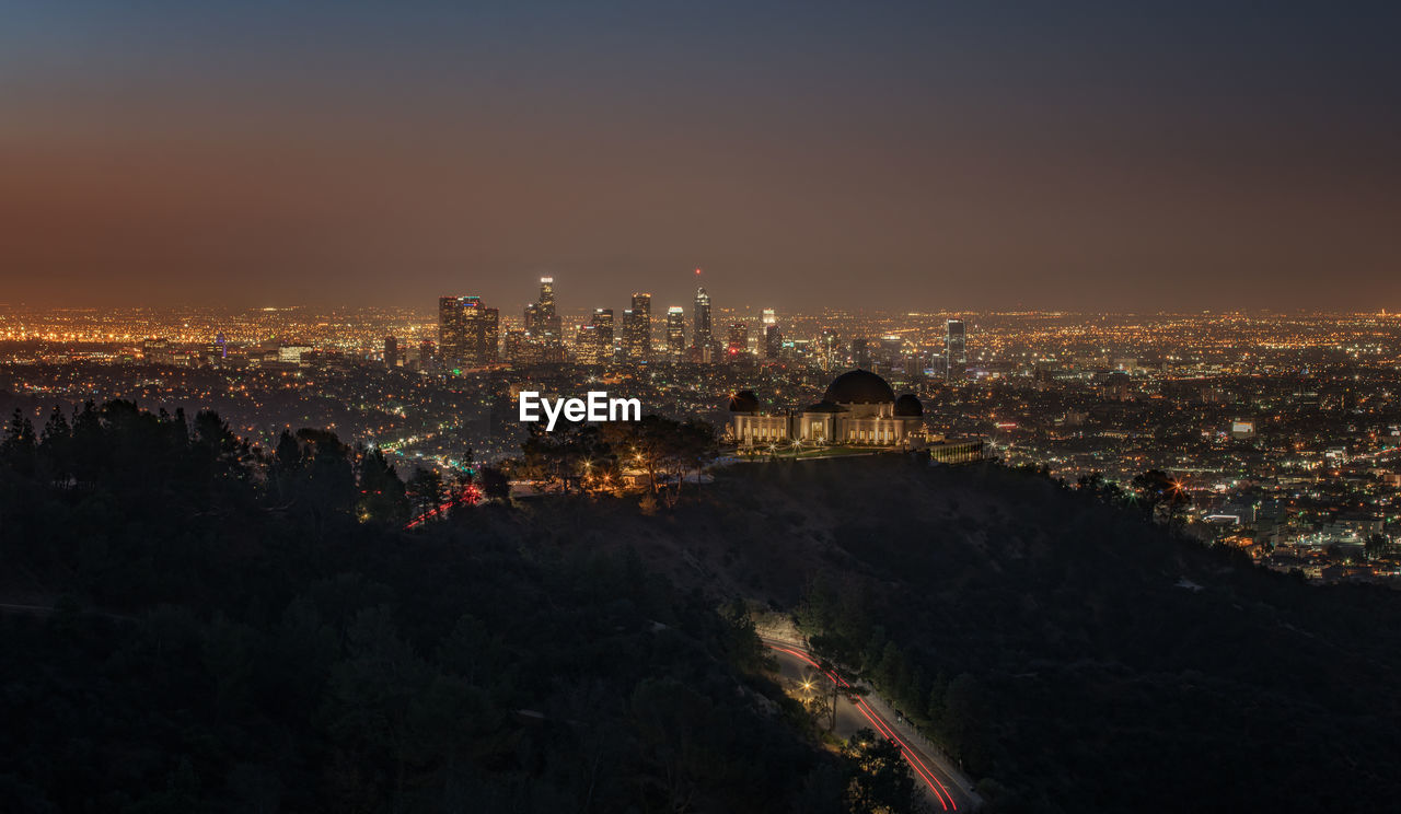 HIGH ANGLE VIEW OF ILLUMINATED CITY AGAINST SKY AT NIGHT