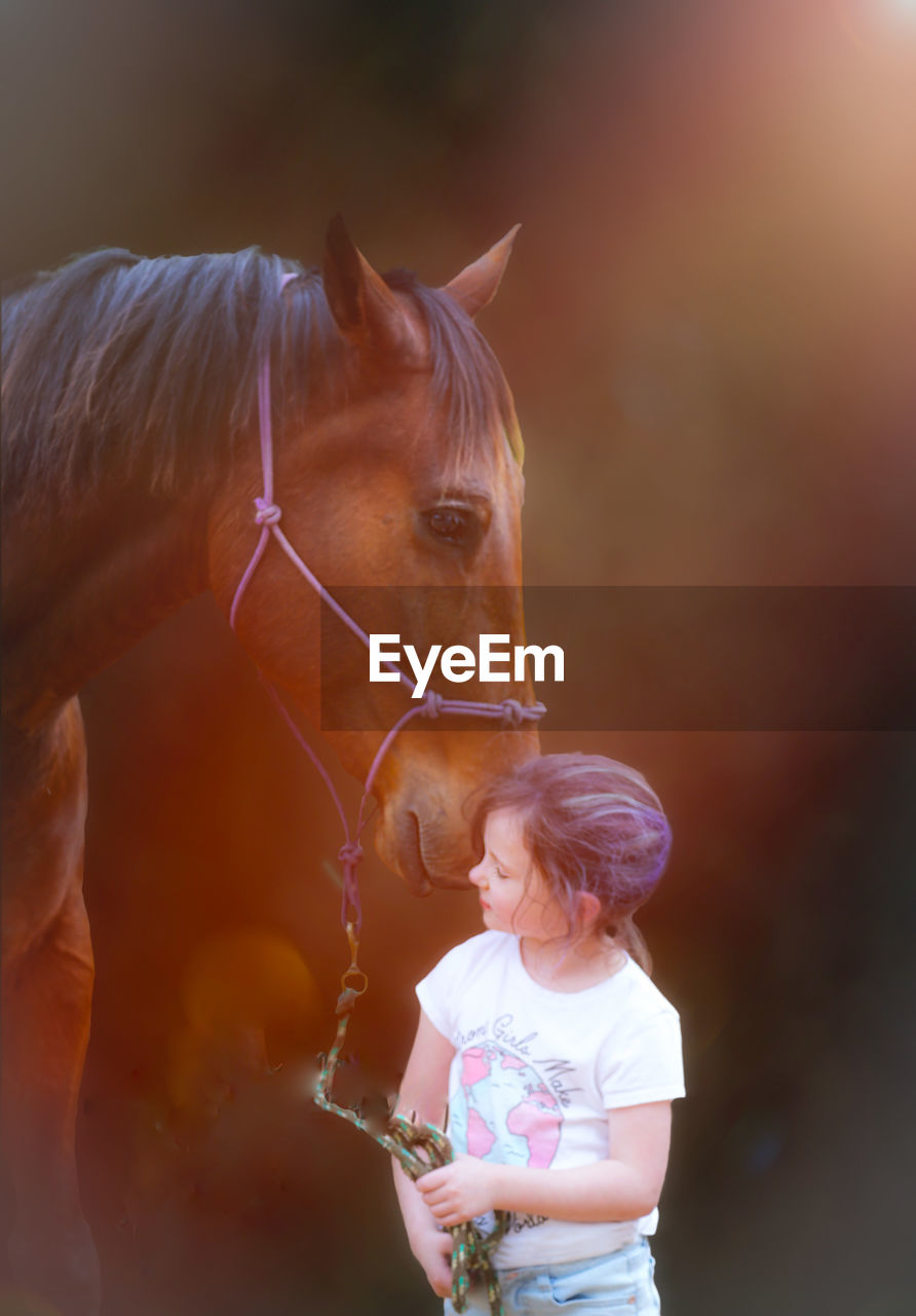 Girl with horse standing outdoors