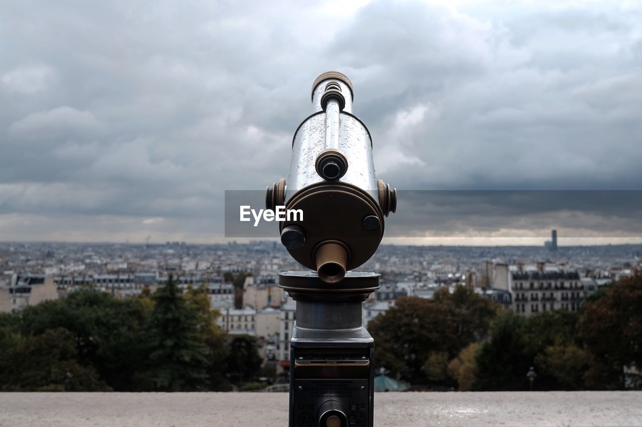 Close-up of coin-operated binoculars against cityscape