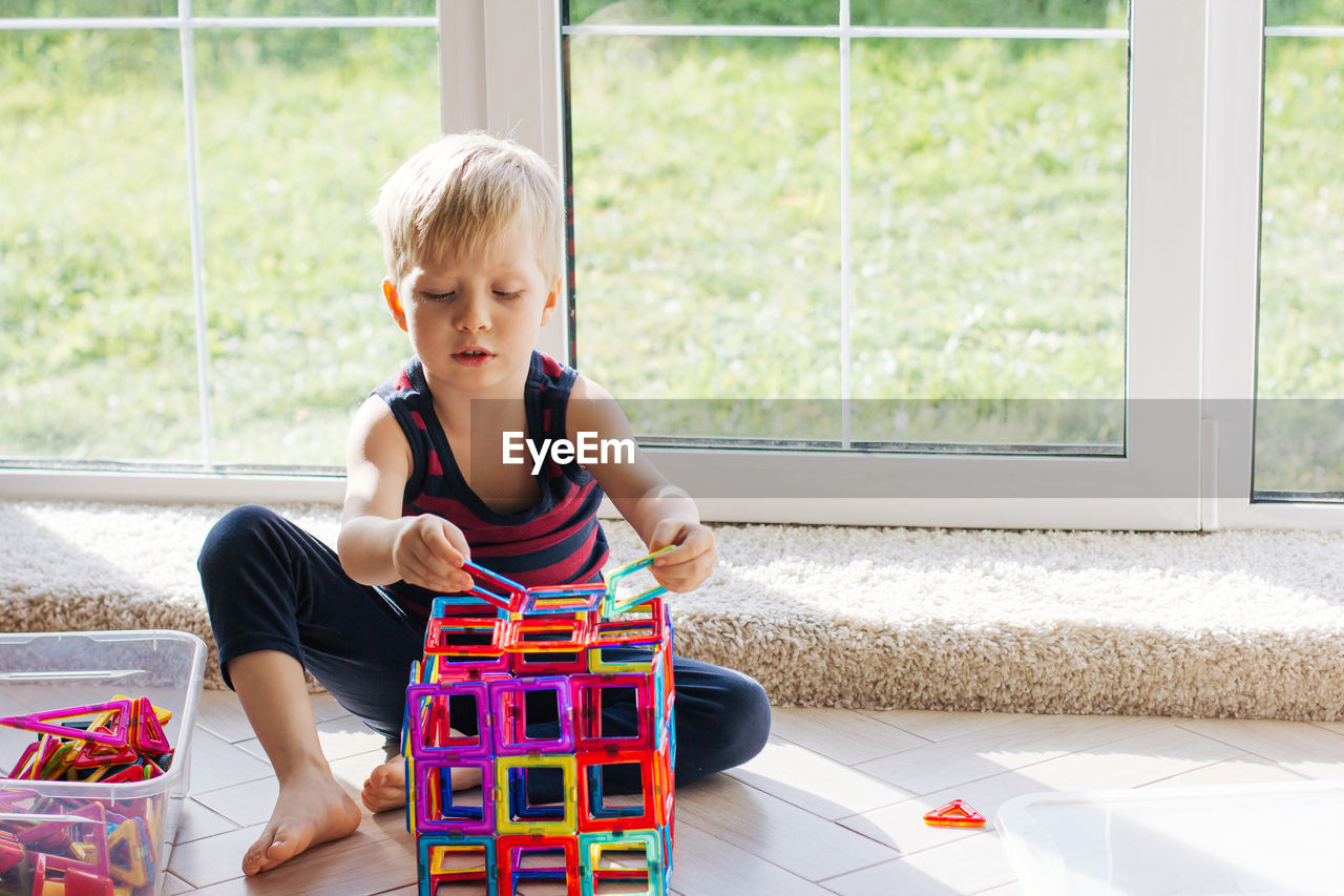 The child is playing with a multi-colored magnetic constructor, building a tower. educational toys 