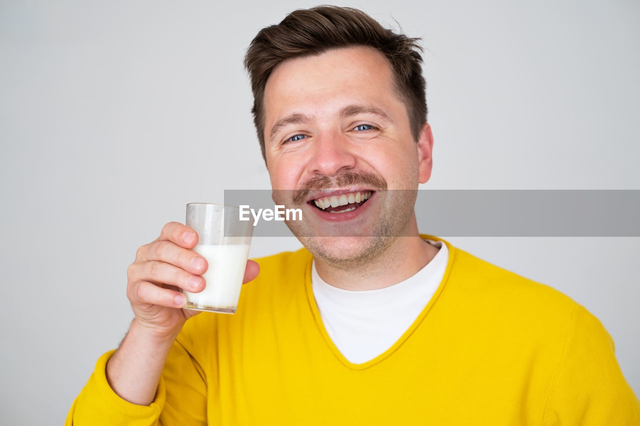 portrait of young woman drinking milk against white background