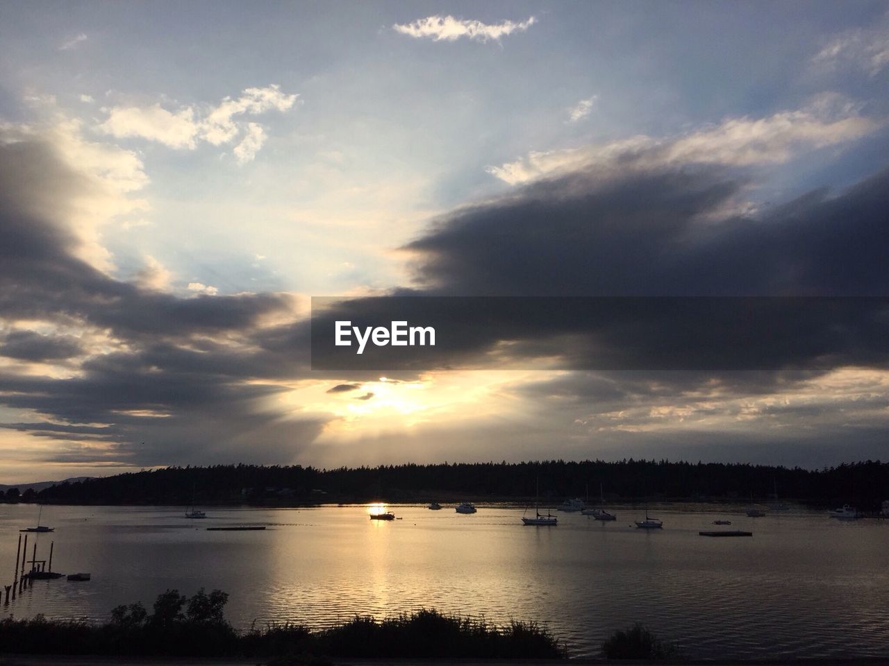 Scenic view of lake against cloudy sky during sunset