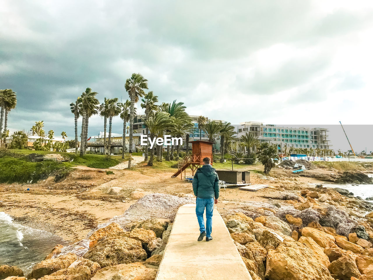 MAN STANDING ON ROCKS AGAINST SKY