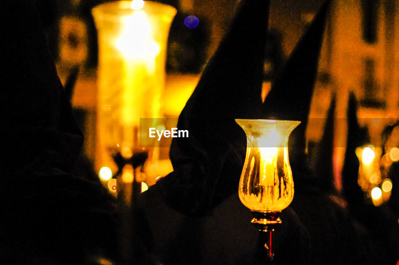 CLOSE-UP OF LIT TEA LIGHT CANDLES IN DARK ROOM