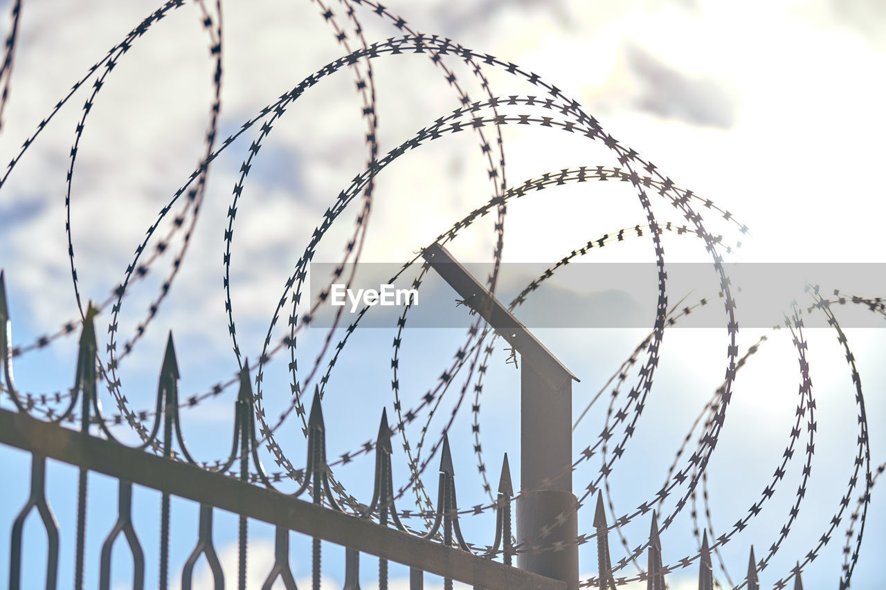 Barbed wire on fence, steel grating fence, metal fence wire. coiled razor wire with sharp barbs