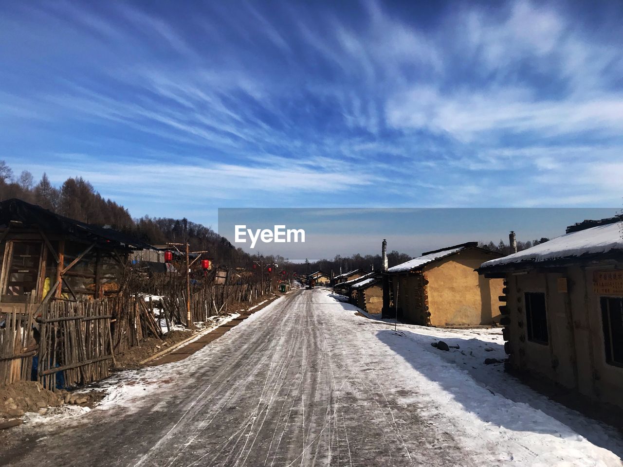 Road amidst buildings against sky during winter