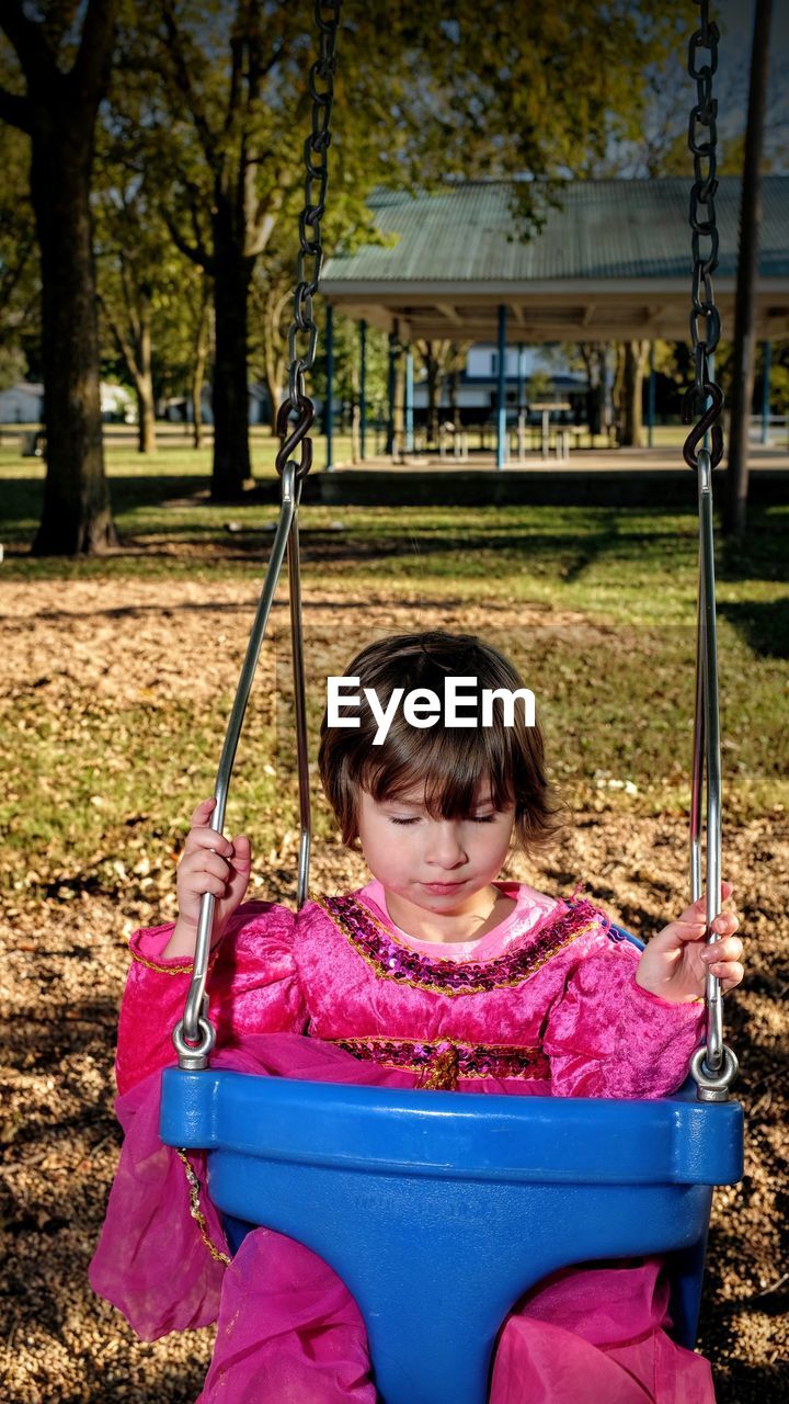 Close-up of girl on swing at playground