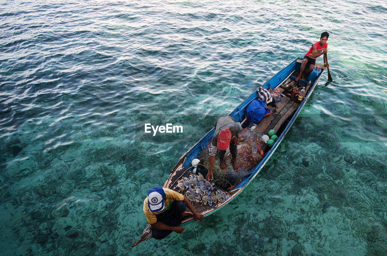 HIGH ANGLE VIEW OF MEN IN BOAT ON SEA