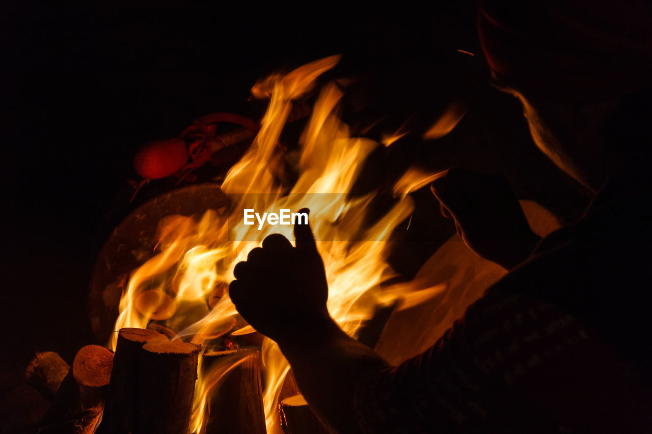 CLOSE-UP OF A PERSON AT THE BONFIRE