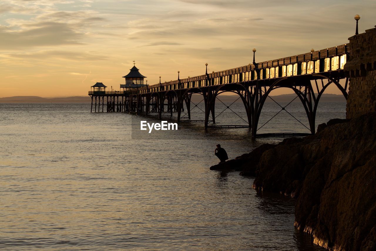 Silhouette of bridge over sea during sunset