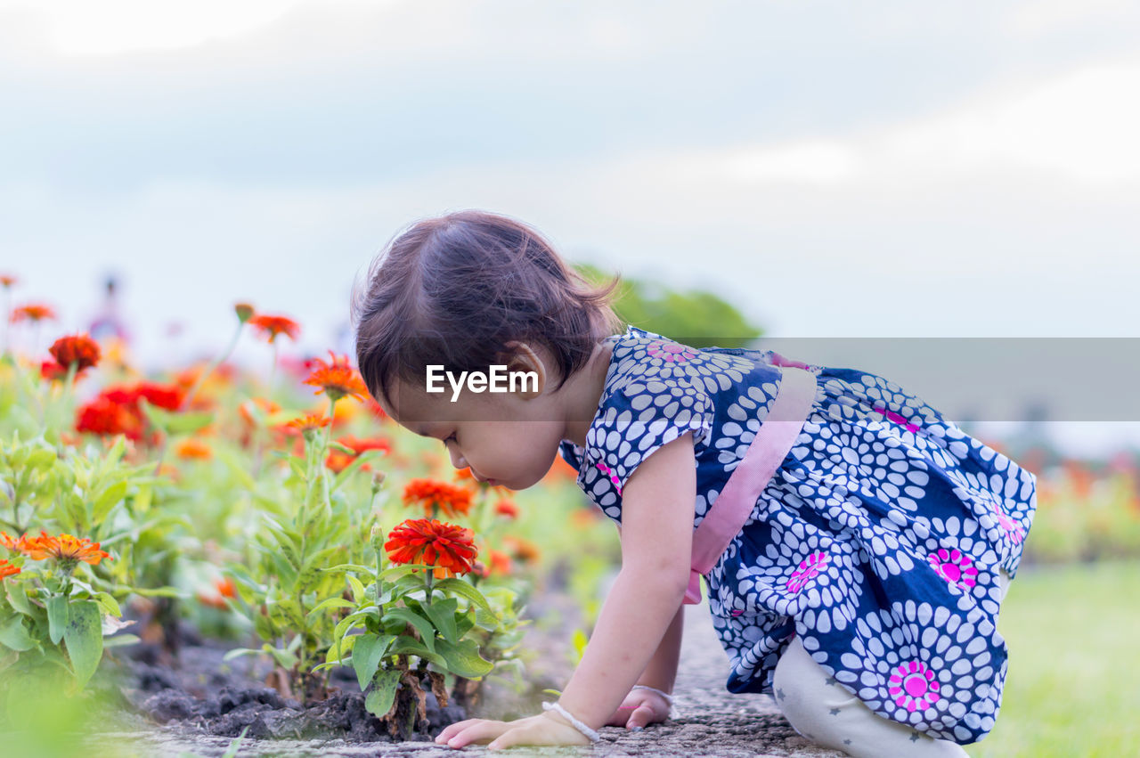 Side view of girl looking at flowering plants