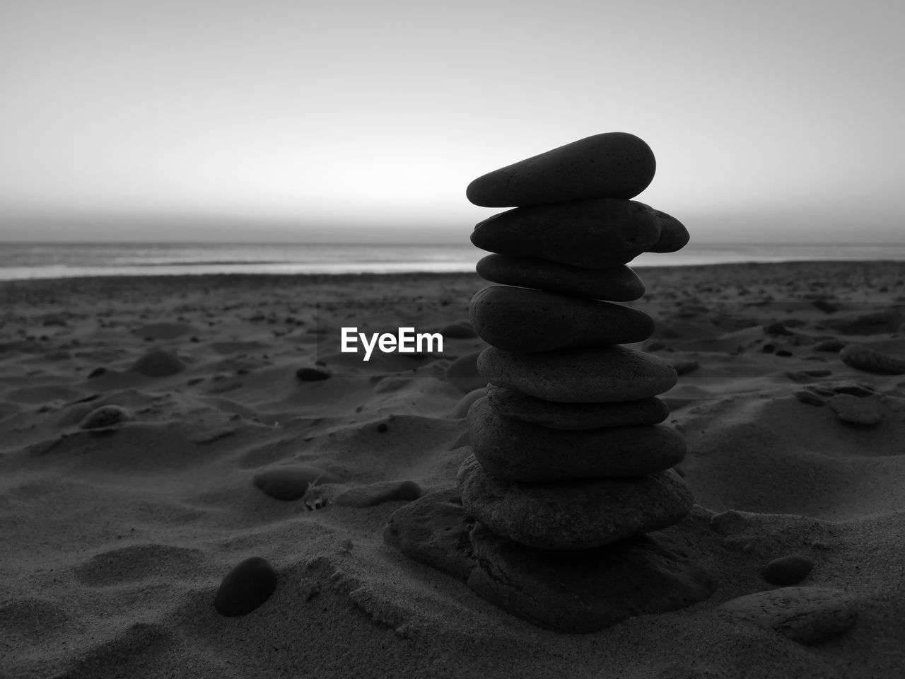 STACK OF PEBBLES ON BEACH AGAINST SKY