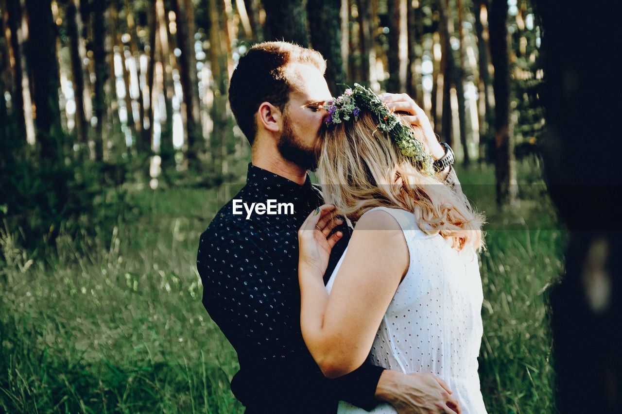 YOUNG COUPLE STANDING BY TREE