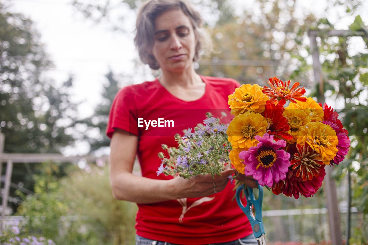 A woman gardener holds out a bright bouquet of wildflowers