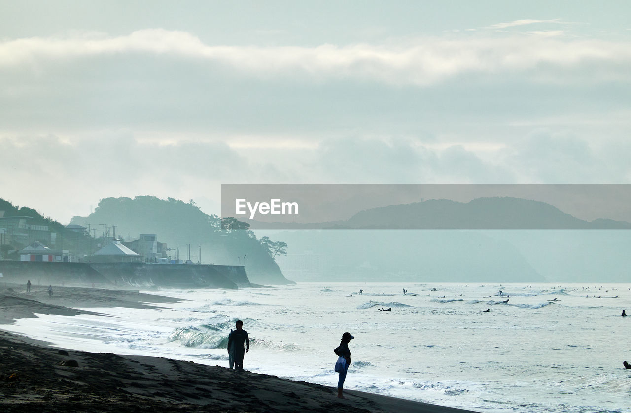 People standing on beach against sky