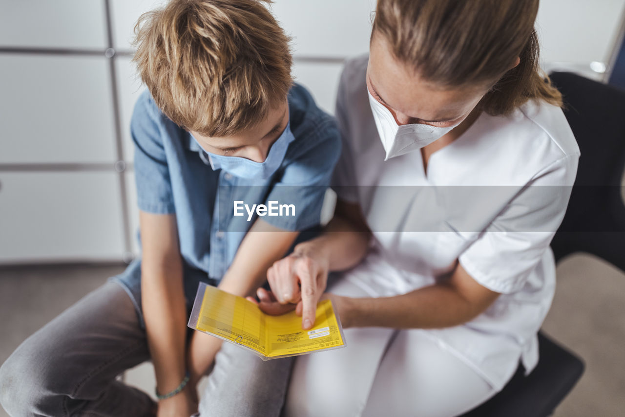 Nurse explaining vaccination certificate to boy at healthcare center