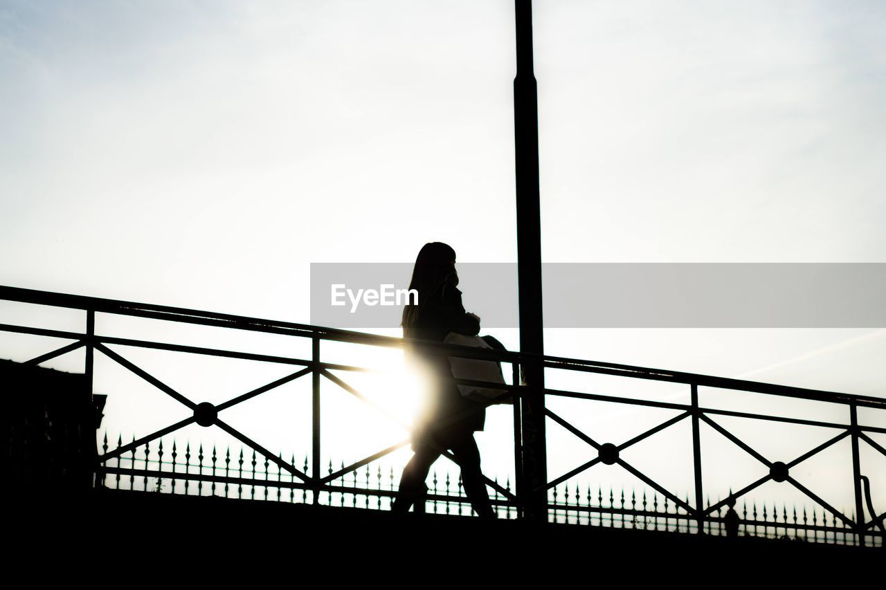 Silhouette woman standing on bridge against sky