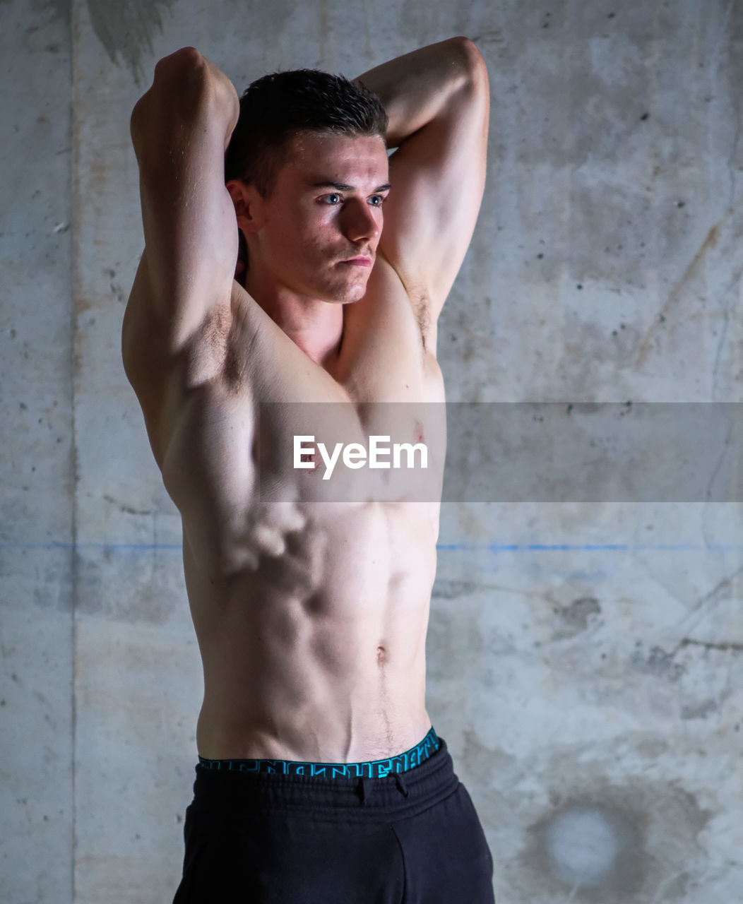 Young muscular man standing against wall