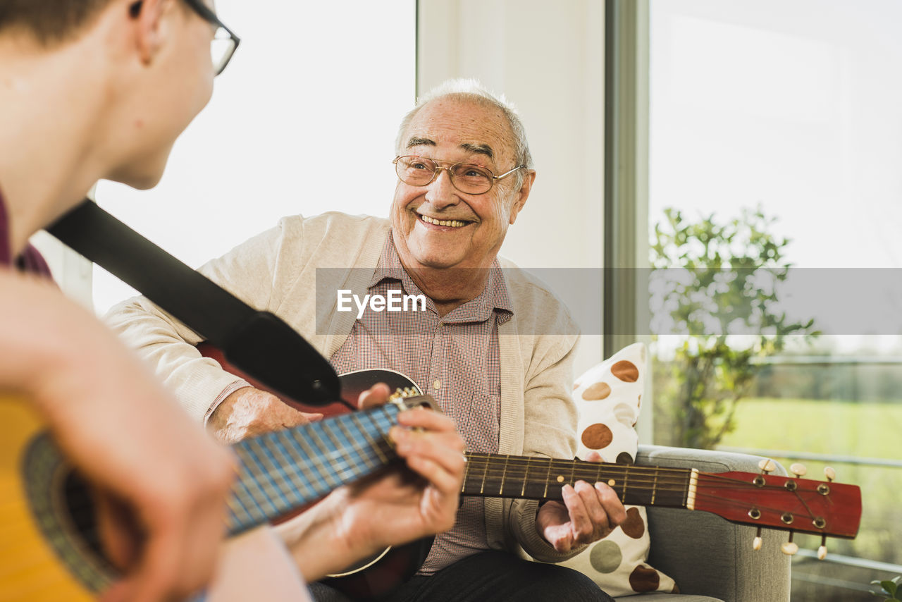 Portrait of senior man playing guitar with his grandson