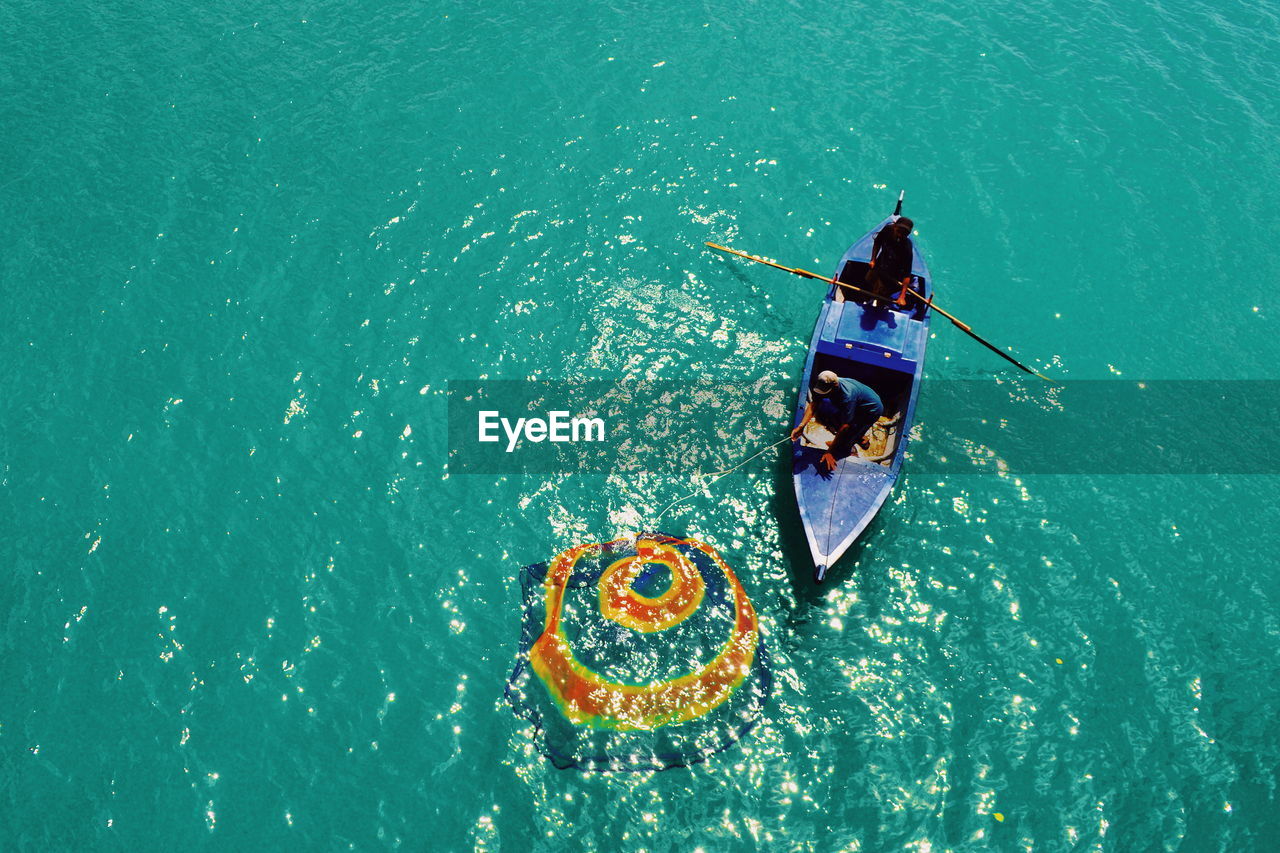 HIGH ANGLE VIEW OF MAN WITH UMBRELLA ON BOAT